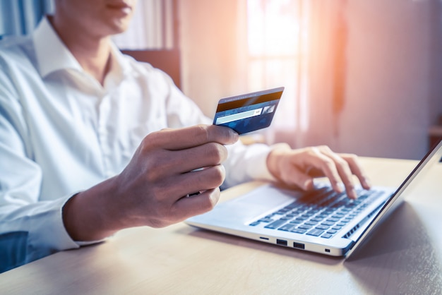 Молодой человек использует кредитную карту для покупок в Интернете
