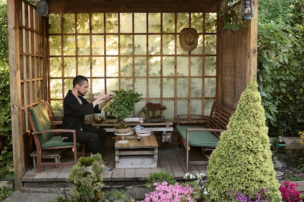 A young man use scissors to decorate the branches of a new bonsai tree in a garden house