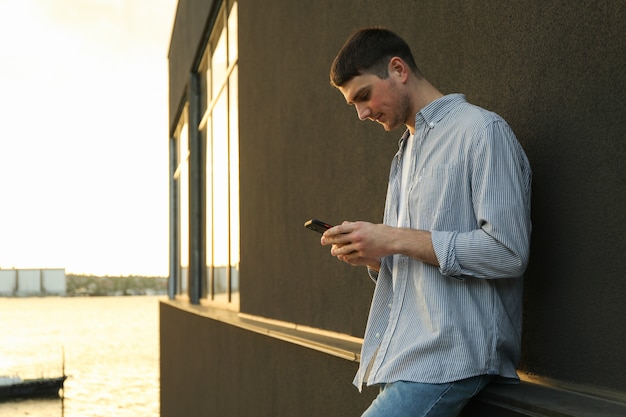 Young man uses a phone outdoor.