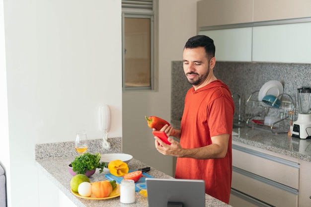 Young man uses smartphone in the kitchen
