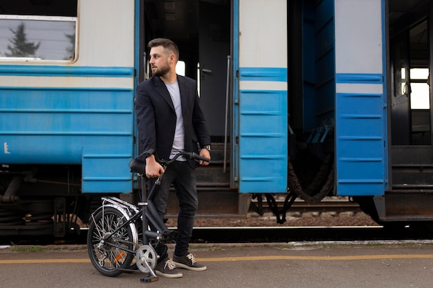 写真 電車で旅行中に折りたたみ自転車を使用して若い男