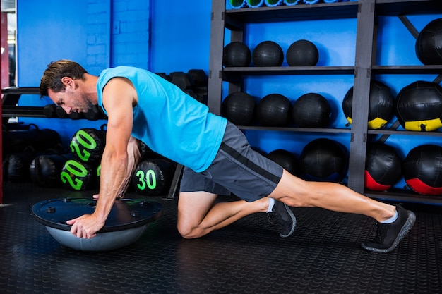 Young man using BOSU ball in gym