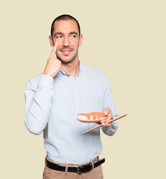 Young man using chopsticks to eat sushi