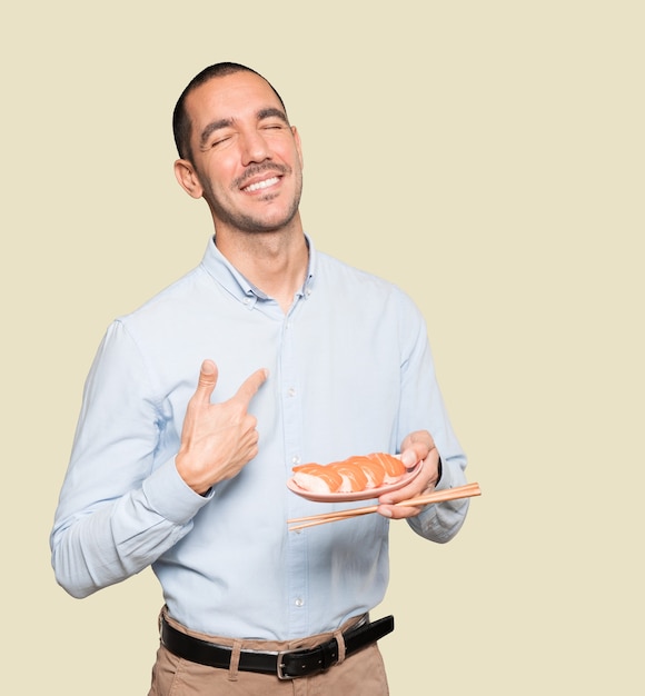 Young man using chopsticks to eat sushi