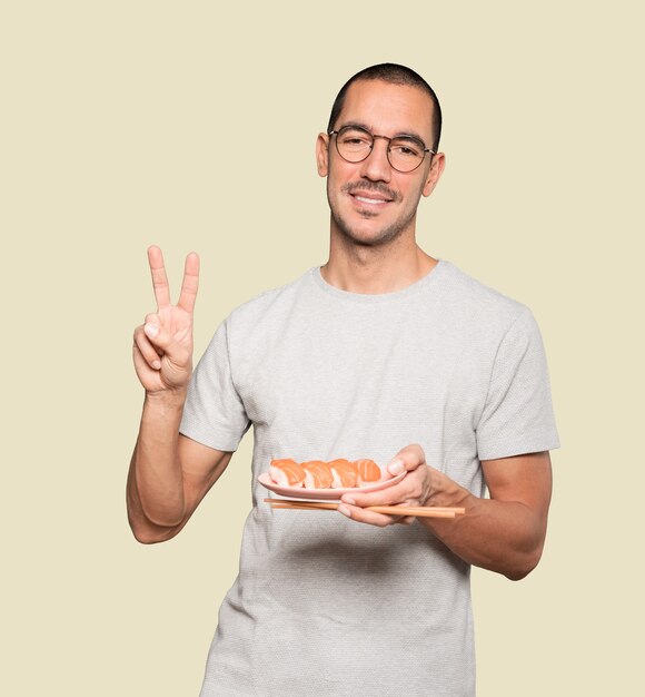 Young man using chopsticks to eat sushi