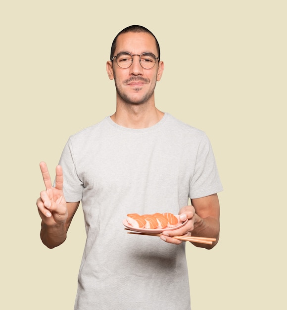 Young man using chopsticks to eat sushi