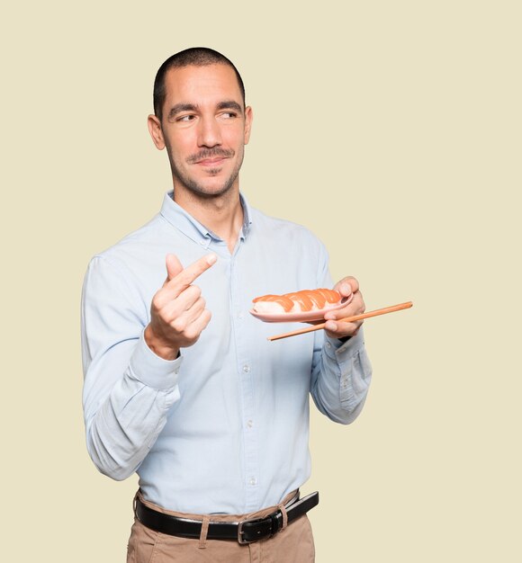 Young man using chopsticks to eat sushi