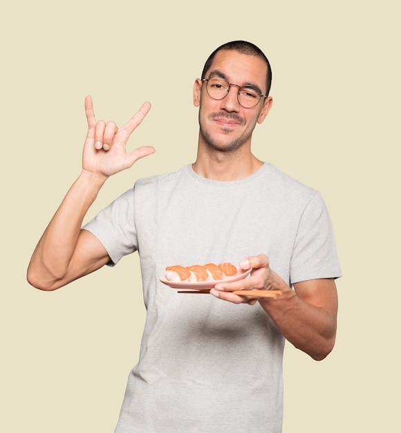 Young man using chopsticks to eat sushi