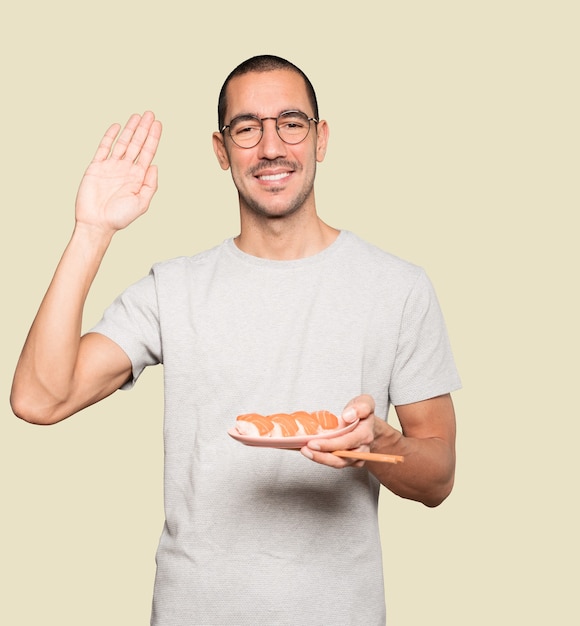 Young man using chopsticks to eat sushi