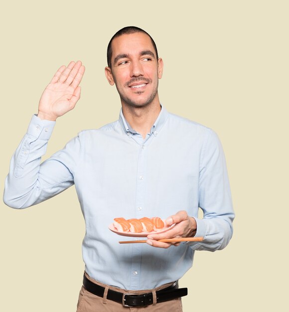 Young man using chopsticks to eat sushi