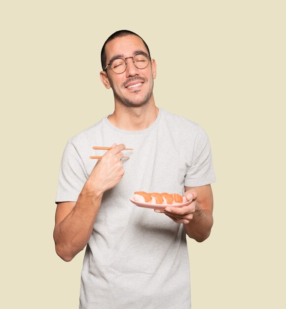 Young man using chopsticks to eat sushi