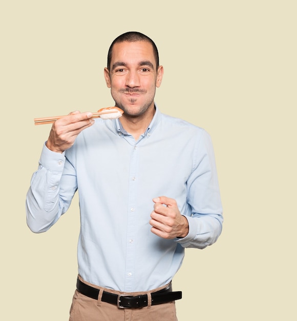 Young man using chopsticks to eat sushi