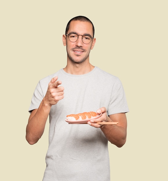 Young man using chopsticks to eat sushi