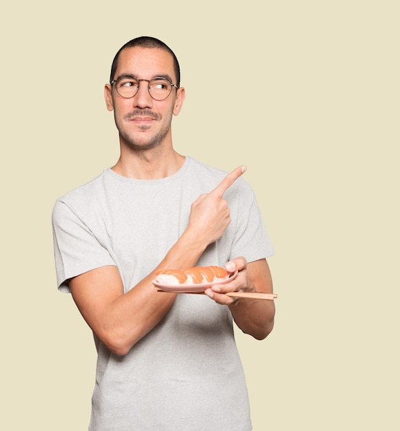 Young man using chopsticks to eat sushi