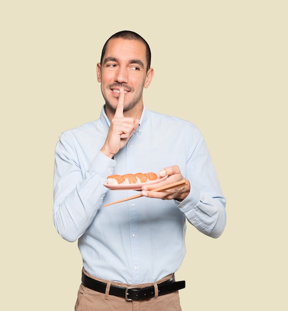 Young man using chopsticks to eat sushi