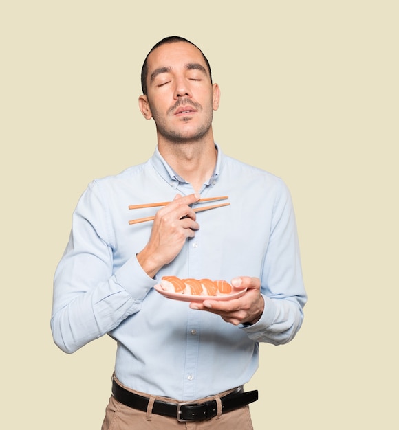 Young man using chopsticks to eat sushi