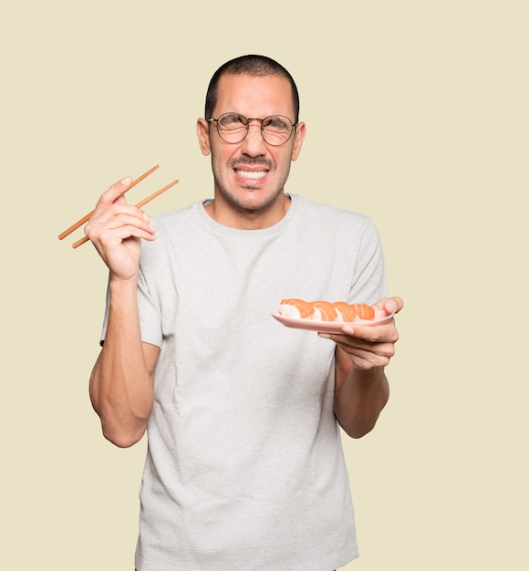 Young man using chopsticks to eat sushi