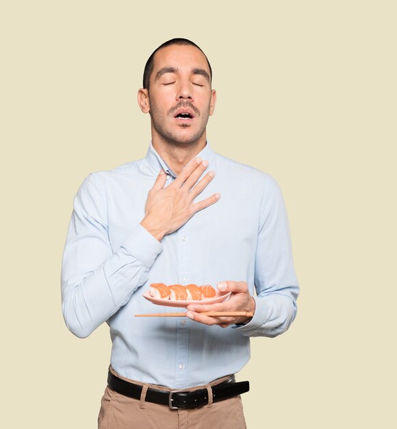 Young man using chopsticks to eat sushi