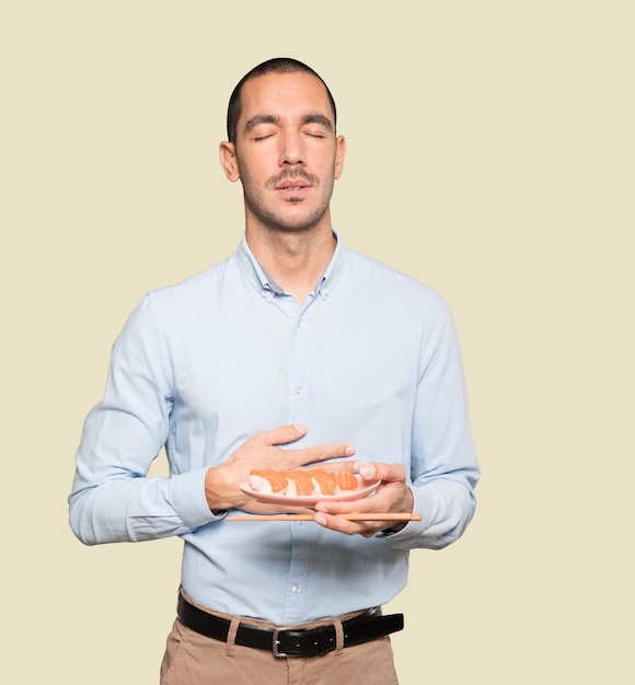 Young man using chopsticks to eat sushi