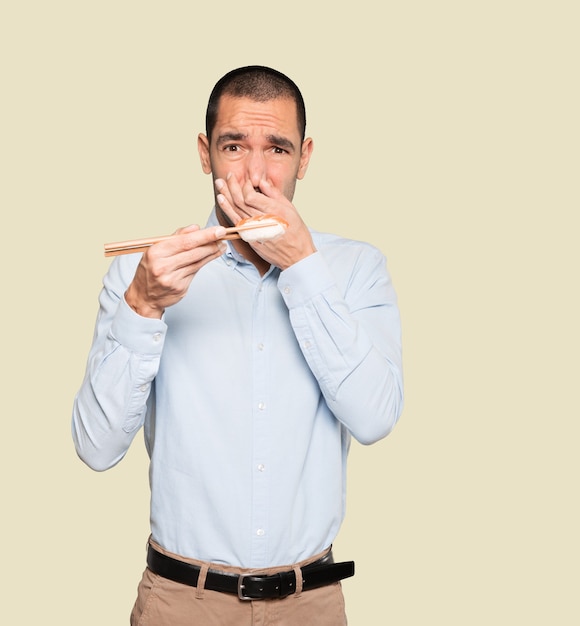 Young man using chopsticks to eat sushi