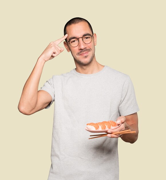 Young man using chopsticks to eat sushi