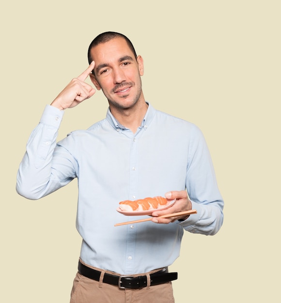 Young man using chopsticks to eat sushi