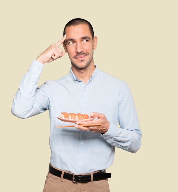 Young man using chopsticks to eat sushi