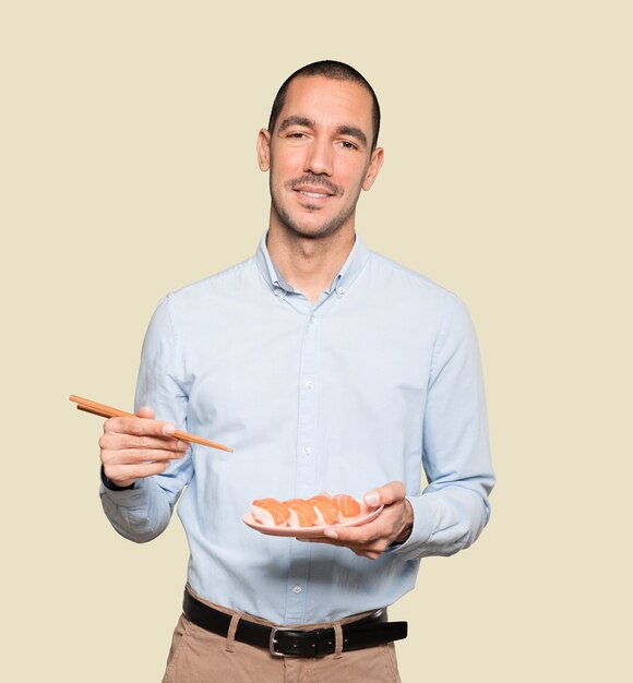 Young man using chopsticks to eat sushi