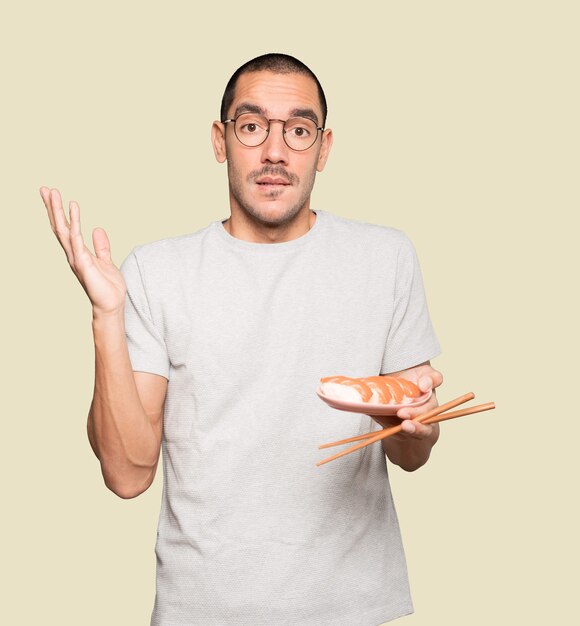 Photo young man using chopsticks to eat sushi