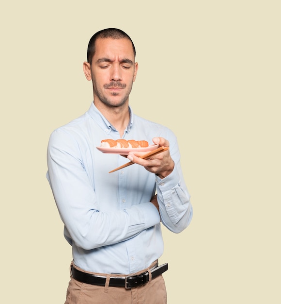 Young man using chopsticks to eat sushi