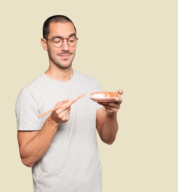 Young man using chopsticks to eat sushi