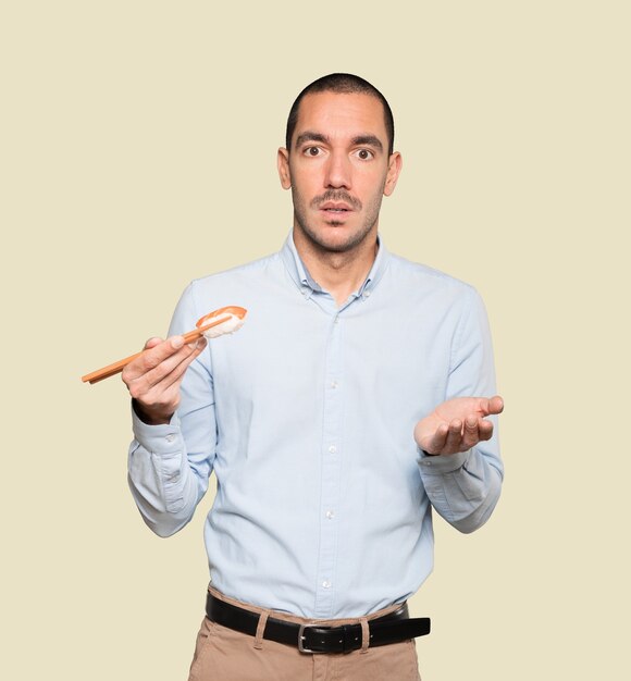 Young man using chopsticks to eat sushi