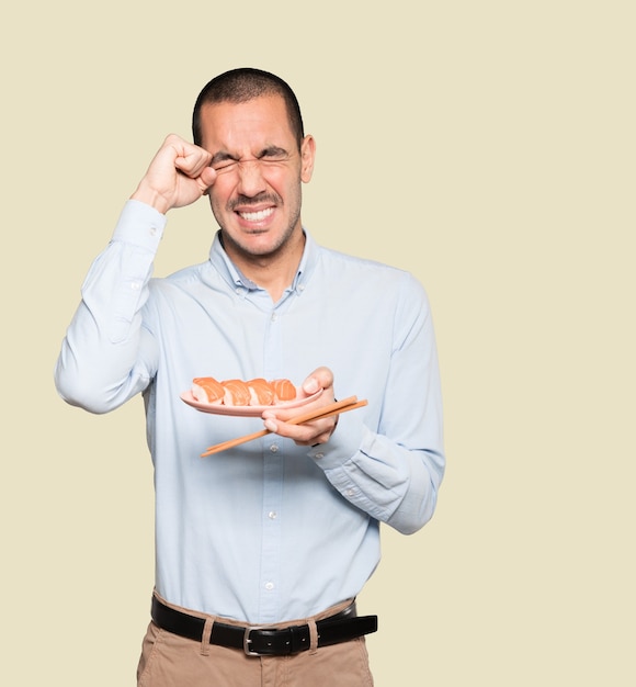 Young man using chopsticks to eat sushi