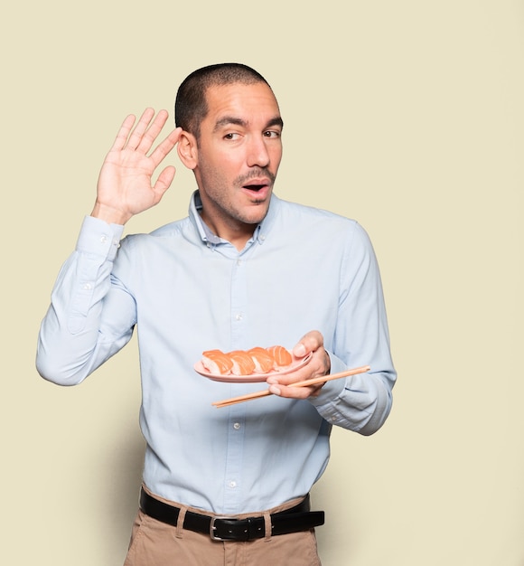 Young man using chopsticks to eat sushi