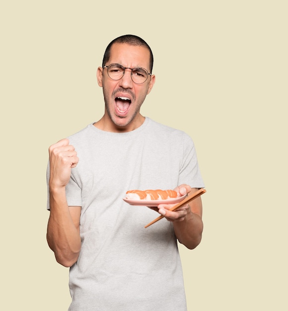 Young man using chopsticks to eat sushi