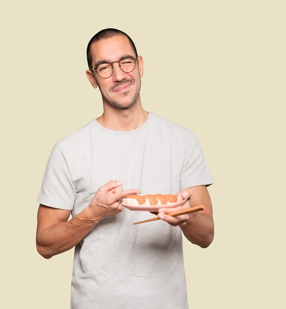 Young man using chopsticks to eat sushi