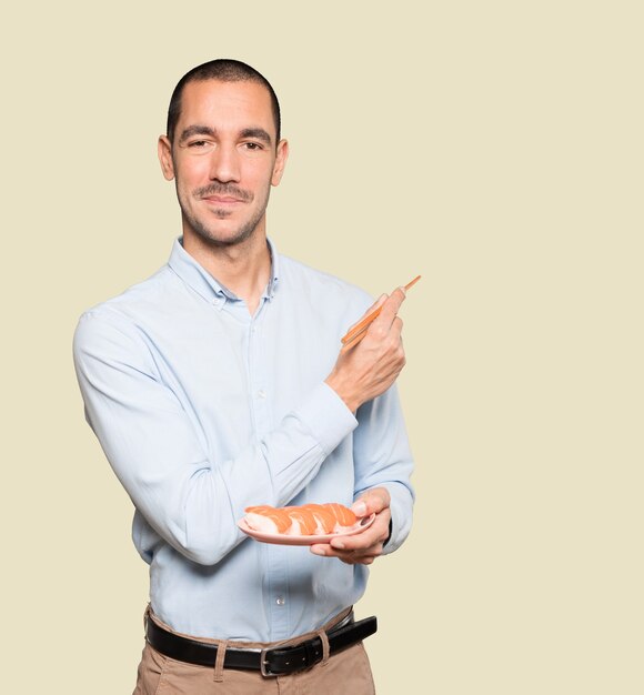 Young man using chopsticks to eat sushi