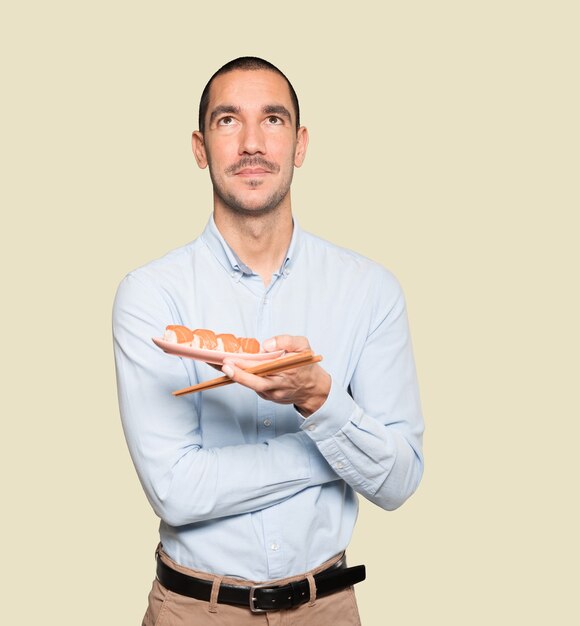 young man using chopsticks to eat sushi