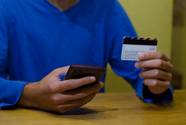 Young man using credit card with his phosing credit card with his phone consumer concept