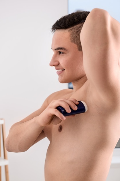 Foto giovane che utilizza il deodorante in bagno