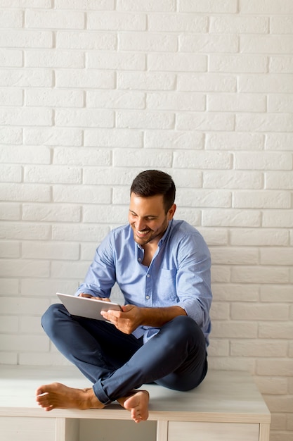 Young man using digital tablet in the room by wall