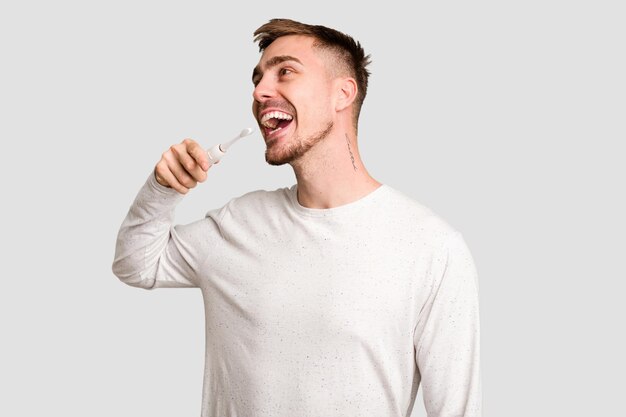 Young man using an electric toothbrush cut out isolated