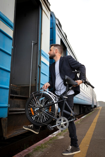 Photo young man using a folding bike while traveling by train