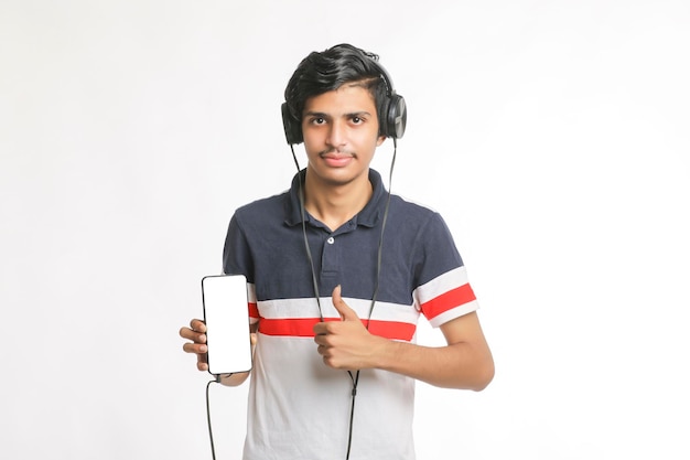 Young man using headphone and showing smartphone on white background.