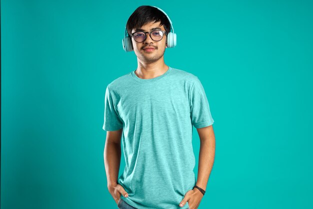 Young man using headphones and smiling isolated over blue background