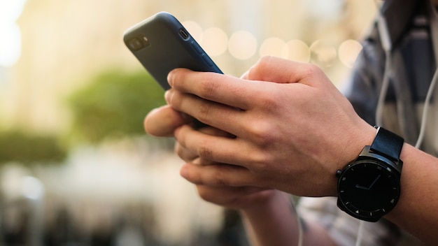 Young man using his mobile phone in city. Close up of a man using mobile smart phone