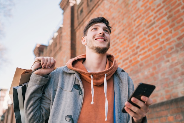 若い男が路上で彼の携帯電話を使用しています。