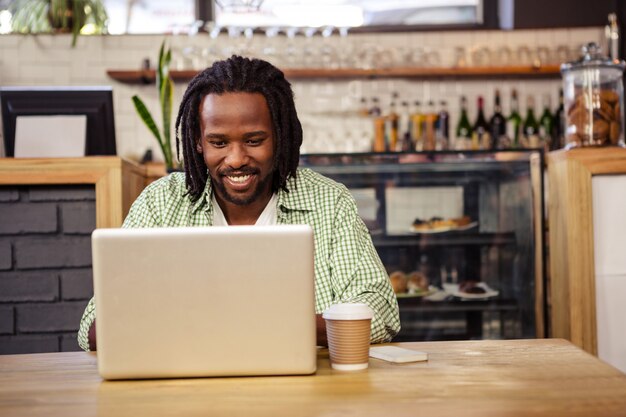 Young man using laptop in cafeteria