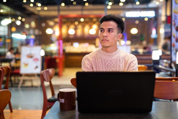 Giovane che utilizza il computer portatile alla caffetteria