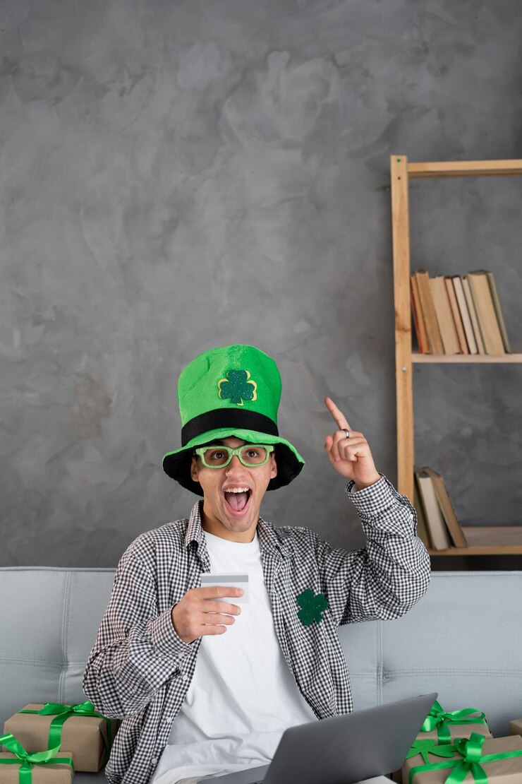 फोटो young man using laptop and credit card to shop online for st patricks day finance and banking at home on sofa have an idea